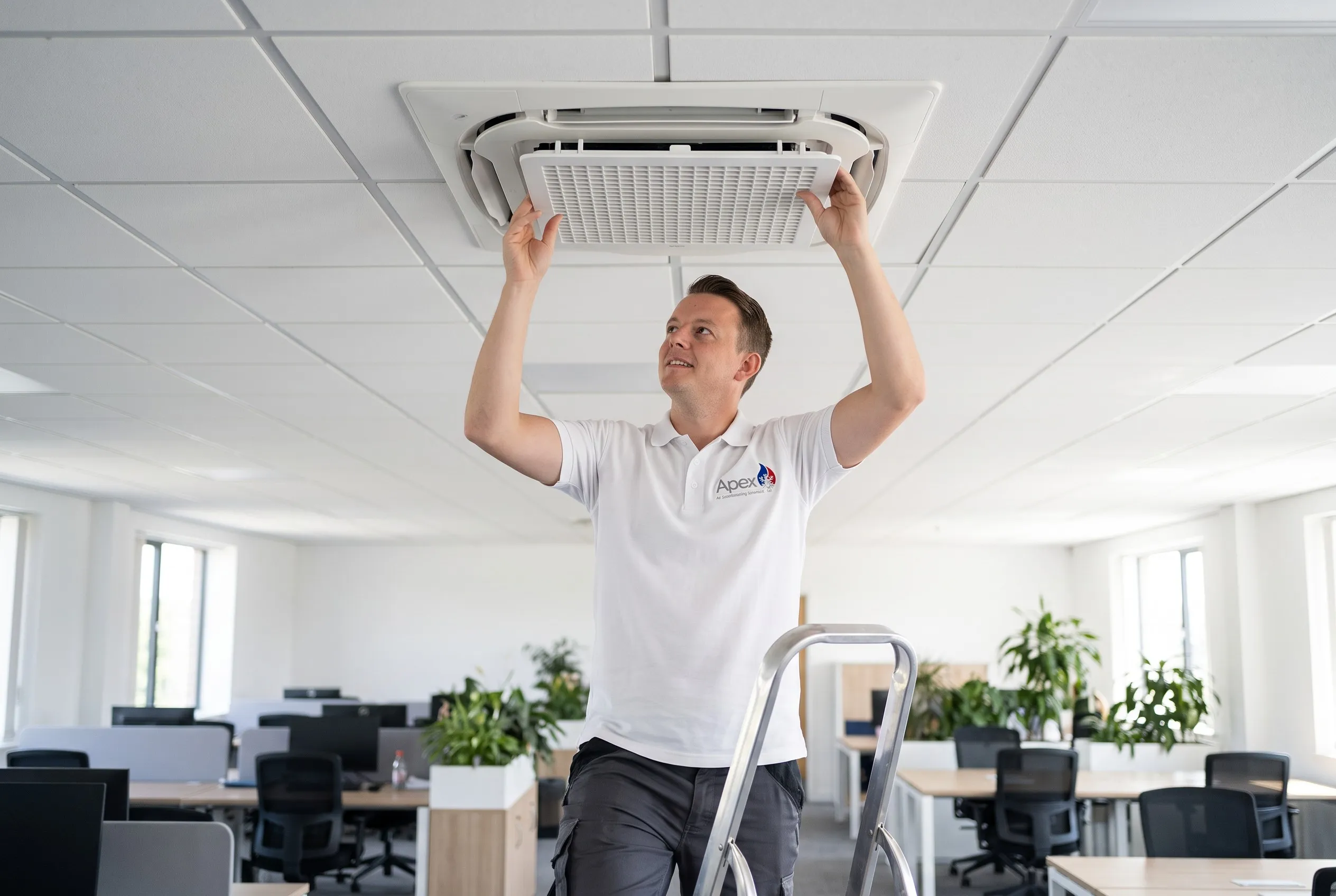Olly fitting the grille of a ceiling cassette in an office