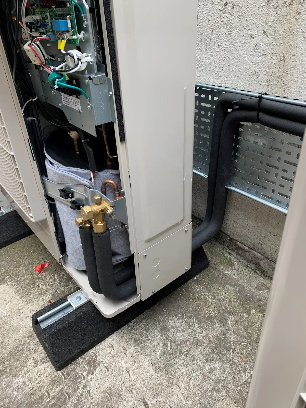An outdoor unit opened up with insulated pipework